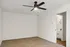 Bright and spacious room with plush carpet, modern ceiling fan, and adjacent bathroom entrance.