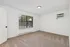 Bright and airy white-walled bedroom with plush carpet and large window, offering scenic views and ample natural light.