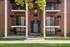 Charming brick apartment exterior with elegant columns, lush greenery, and inviting balconies.