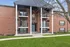 Charming brick apartment building with elegant balconies and a welcoming entrance, surrounded by lush green grass.