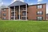 Charming brick apartment building with elegant balconies and lush green lawn, offering modern living in a tranquil setting.