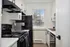 Contemporary kitchen with sleek black appliances, modern white cabinetry, and a scenic window view creating a bright, inviting space.