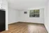 Bright and spacious living area with elegant wood flooring, large windows for natural light, and a sleek air conditioning unit for comfort.