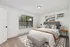 Inviting modern bedroom with large window, cozy bed, chic artwork, and stylish lighting, offering a relaxing atmosphere.
