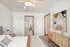 Serene bedroom showcasing modern decor with a stylish wooden dresser, large abstract wall art, and a cozy bed, leading to a bright hallway.
