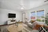 Inviting living room with modern decor, featuring a cozy armchair, large window with outdoor view, and stylish entertainment setup.