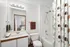 Bright and modern bathroom featuring a sleek sink, bathtub with geometric shower curtain, and a large mirror reflecting a stylish room.