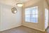 Cozy and bright room with soft carpet flooring, stylish geometric mirror, and inviting natural light streaming through large windows with blinds.