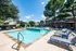 Inviting outdoor pool area with cozy lounge chairs, shaded umbrellas, and lush greenery, perfect for relaxation and leisure.
