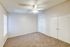 Bright, spacious bedroom featuring plush carpeting, a ceiling fan, large closets, and natural light streaming through a window.