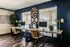 Elegant home office with dual workstations, stylish dark blue walls, modern decor, and ample natural light.