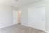 Bright and inviting bedroom with plush carpeting, pristine white closet doors, and modern entryway.