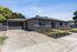 Charming single-story home with modern gray facade, landscaped front yard, and spacious driveway.