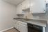 Bright and modern kitchen with sleek countertops, ample white cabinetry, and a built-in dishwasher. Perfect for culinary creativity and storage.