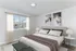 Elegant bedroom showcasing a cozy bed with plush pillows, stylish artwork, ambient lighting, and a sunlit window view.