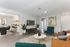 Elegant open-concept living room with modern furniture, a wall-mounted TV, and a view into a stylish dining area with contemporary chairs and decor.