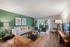 Modern apartment living room with chic decor, featuring a cozy white sofa, stylish green accent wall, and natural light from sliding glass doors.