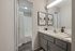 Modern bathroom with sleek gray vanity, elegant marble countertop, tasteful decor, and bright lighting.