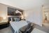 Inviting bedroom with modern decor, cozy bedding, and elegant artwork, offering a serene and stylish atmosphere.