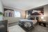 Elegant bedroom with modern decor, featuring plush bedding, stylish artwork, and ample natural light.