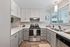 Modern kitchen with sleek cabinetry, stainless steel appliances, and elegant marble countertops, offering a bright and inviting space ideal for cooking enthusiasts.