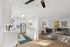 Modern open-plan apartment with a sleek kitchen, cozy living area, and stylish decor, highlighted by natural light streaming through large windows.