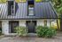 Charming townhouse exterior with sleek metal roof, modern design, and lush greenery.
