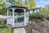 Charming outdoor gazebo with elegant white fencing, surrounded by lush greenery and vibrant autumn trees.
