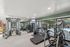 Modern fitness center with a variety of exercise equipment, floor-to-ceiling windows, and a view of the outdoor pool area.