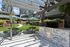 Charming outdoor space with a sleek barbecue grill, cozy picnic tables, vibrant green lawn, and shaded pergola, perfect for gatherings and relaxation.