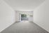 Bright and airy living room with plush carpeting and sliding glass doors leading to a private balcony.