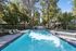 Inviting outdoor pool area surrounded by lush greenery, featuring comfortable lounge chairs and relaxing shade umbrellas.