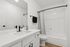 Elegantly designed bathroom with a modern white vanity, sleek black fixtures, and a pristine bathtub with a stylish shower curtain.