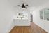 Bright and modern open-plan kitchen with sleek white cabinetry, stainless steel appliances, and elegant ceiling fan accent.
