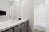 Modern bathroom featuring a sleek vanity with a polished countertop and elegant faucet beside a pristine shower area.