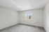 Bright bedroom with soft carpet flooring, large window offering scenic views, and sleek air conditioning unit, ideal for comfort and relaxation.