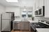 Modern kitchen with sleek stainless steel appliances, elegant white cabinetry, and a stylish window view highlighting natural light and contemporary design.