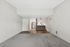 Elegant open-plan interior featuring soft grey walls, cozy carpeted living area, and stylish hardwood flooring leading to a modern kitchen with stainless steel appliances.