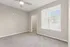 Bright bedroom with plush carpeting, large window with blinds, and a ceiling fan, leading to a spacious walk-in closet.