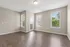 Bright, spacious room with elegant wood flooring and large windows offering lush green views.