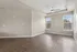 Bright and airy living room with elegant wood flooring, large windows, and modern ceiling fan.