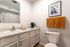 Charming bathroom with modern fixtures, sleek white cabinets, and vibrant orange towels for a pop of color.