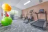 Modern fitness room with vibrant exercise balls, state-of-the-art treadmill, and elliptical machine next to a window with natural light.