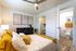 Inviting bedroom with cozy yellow accents, modern dresser, and open walk-in closet, offering a blend of style and comfort.