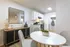 Inviting dining area with modern decor, white cabinets, and sleek kitchen set against a warm hardwood floor backdrop.