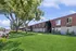 Inviting apartment complex with charming architecture, lush green lawns, and mature trees, offering a serene living environment.