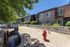 Inviting apartment exterior with lush greenery and a charming play area for kids, featuring a vibrant red hydrant and playful tunnels.