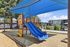 Bright and inviting playground with vibrant blue slides under a shaded canopy, perfect for family-friendly living.
