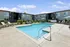 Inviting apartment complex with a sparkling blue swimming pool, lounge chairs, and lush greenery perfect for relaxation.