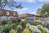 Charming apartment complex with modern design, surrounded by lush landscaping and vibrant flowers, offering a serene living environment.